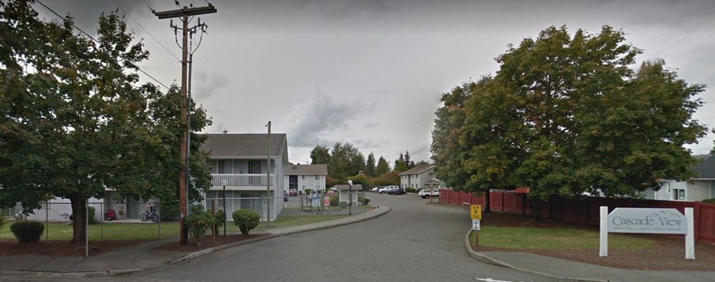 a street with houses and trees and a cloudy sky