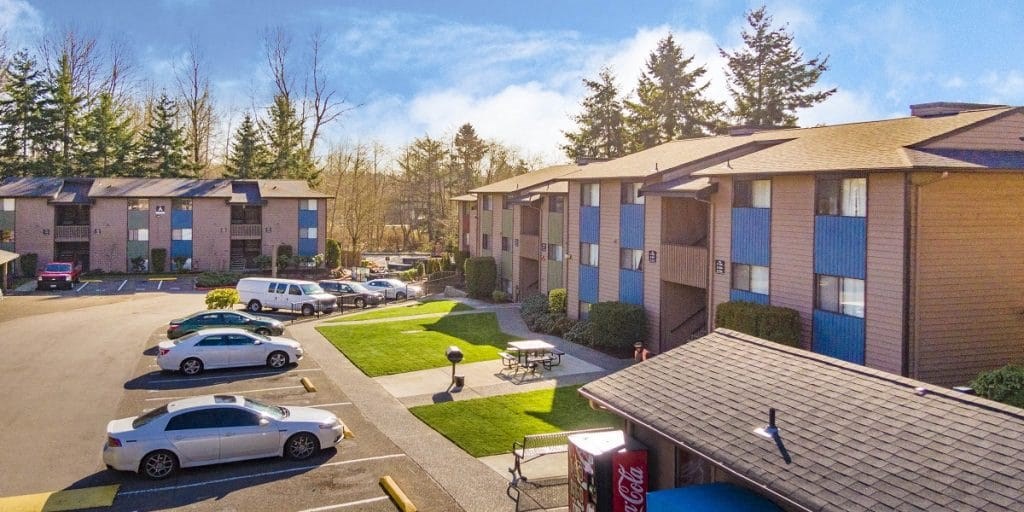 a row of apartment buildings with cars parked in a parking lot