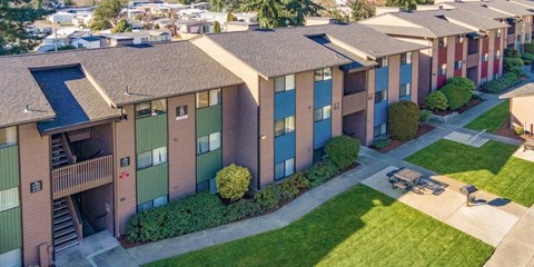 an aerial view of a row of apartment buildings with green lawns and trees