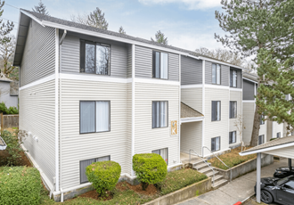 the outlook of an apartment building with white siding and green landscaping