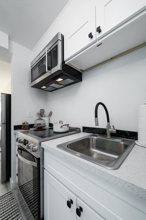 A modern kitchen with a stainless steel sink and black appliances.