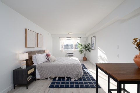 A bedroom with a bed, nightstand, and a window.