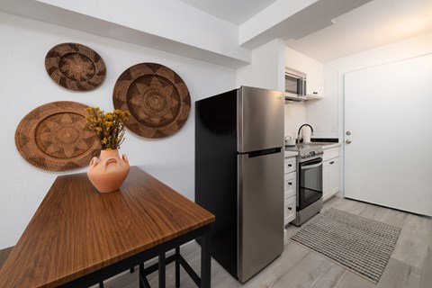 A kitchen with a black refrigerator and wooden table.
