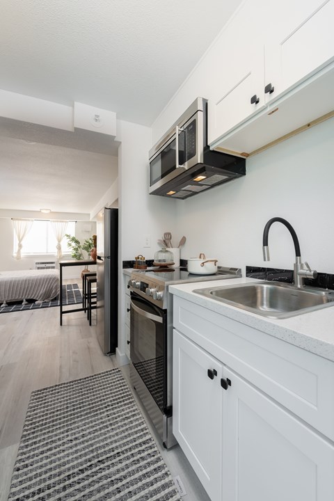 A modern kitchen with white cabinets and a black stove top oven.