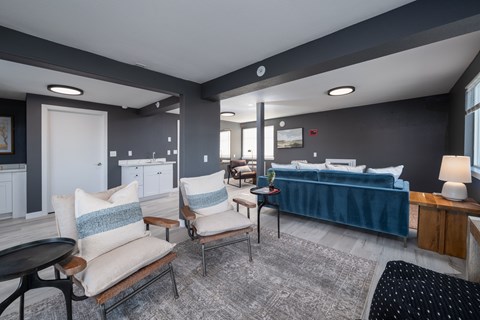 A living room with a blue couch and a grey rug.