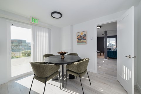 A dining room with a table and chairs and an exit sign on the wall.