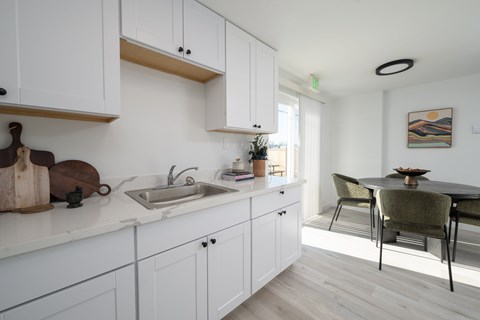 A kitchen with white cabinets and a wooden cutting board on the counter.
