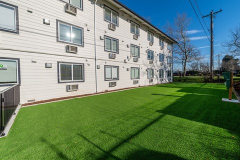 A grassy area in front of a building with a clear blue sky.