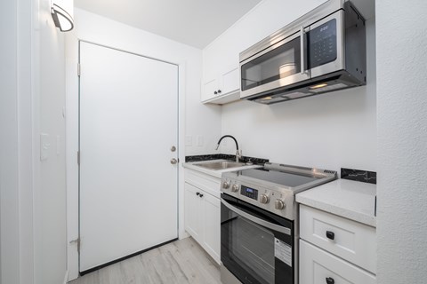 A white kitchen with a black microwave above the stove.