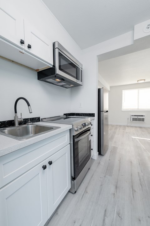 A modern kitchen with white cabinets and stainless steel appliances.