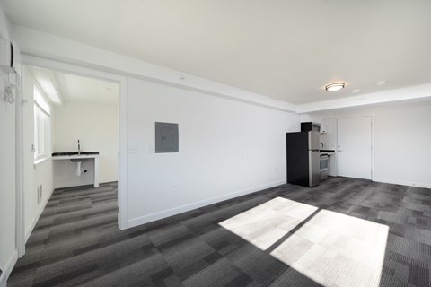 A room with a white wall and a black fridge.