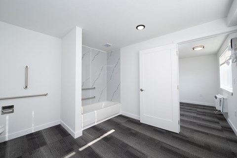 A white bathroom with a marble wall and a window.