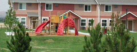 a playground with a red slide in front of a house