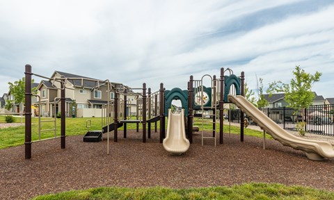 A playground with a slide, swings, and a seesaw.