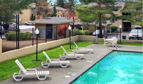 a swimming pool with chaise lounge chairs in front of a house