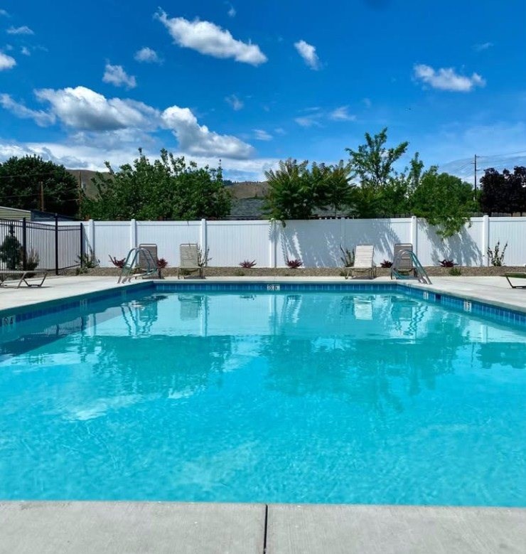 a resort style swimming pool with chairs and a patio