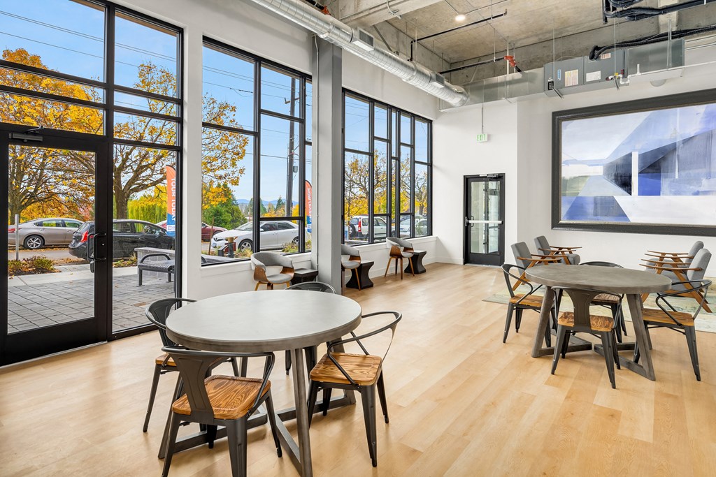 a dining room with tables and chairs and large windows