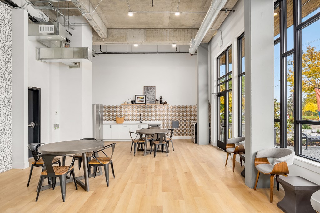 a dining room with tables and chairs and a kitchen with large windows