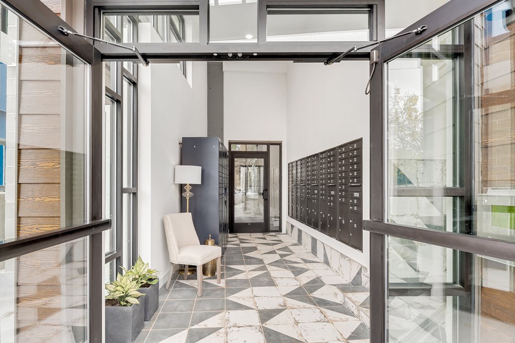 a hallway with glass doors and a seating area with a chair