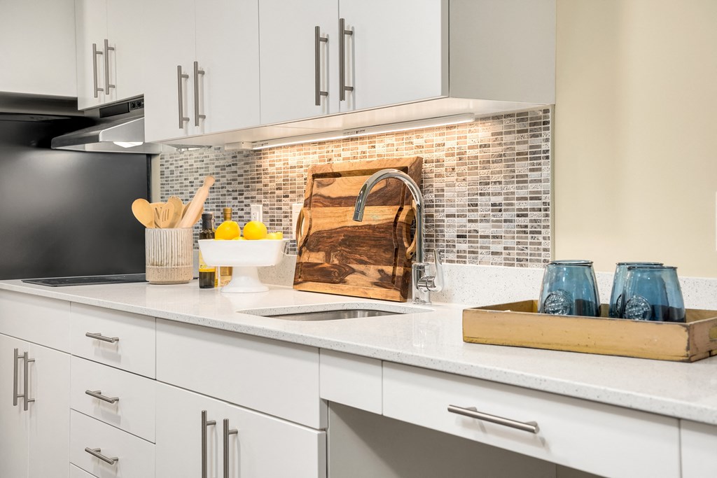 a kitchen with white cabinets and a sink and a wooden cutting board