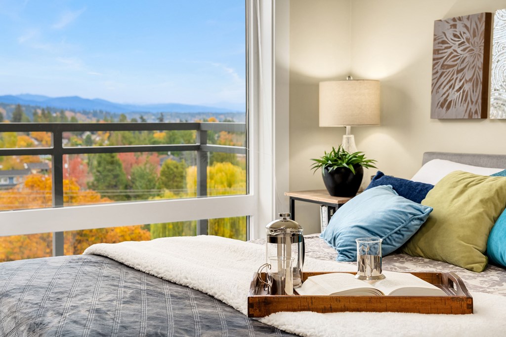 a bedroom with a large window and a bed with pillows and a tray