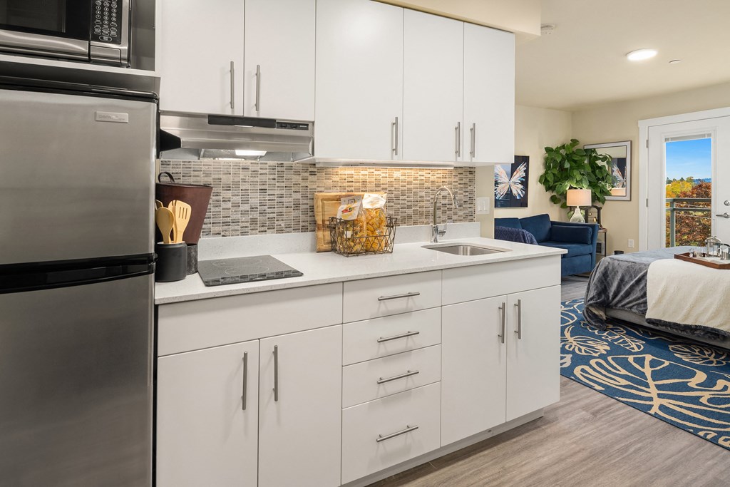 a kitchen with white cabinets and a sink and a refrigerator