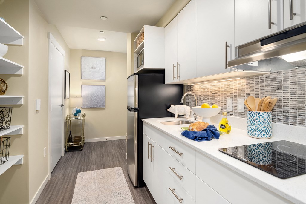 a kitchen with white cabinets and a black refrigerator