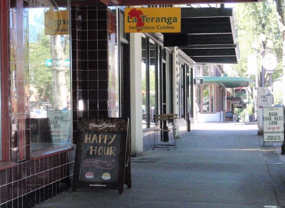 a sign for a happy hour on the sidewalk