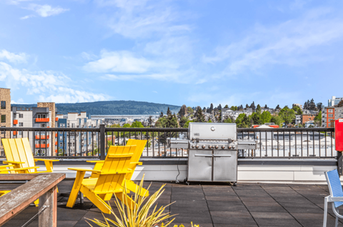 the rooftop patio with yellow chairs and a grill and a view of the city