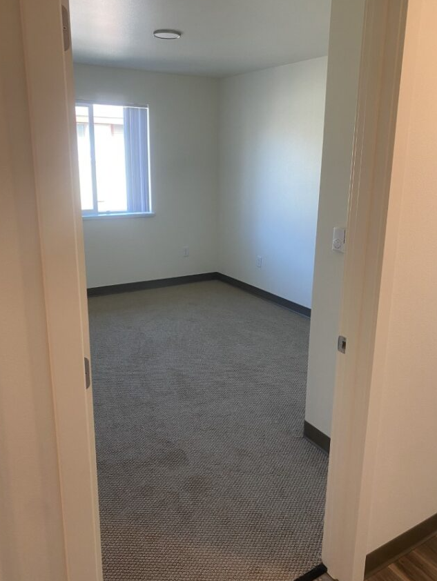 an empty room with a window and a carpeted floor