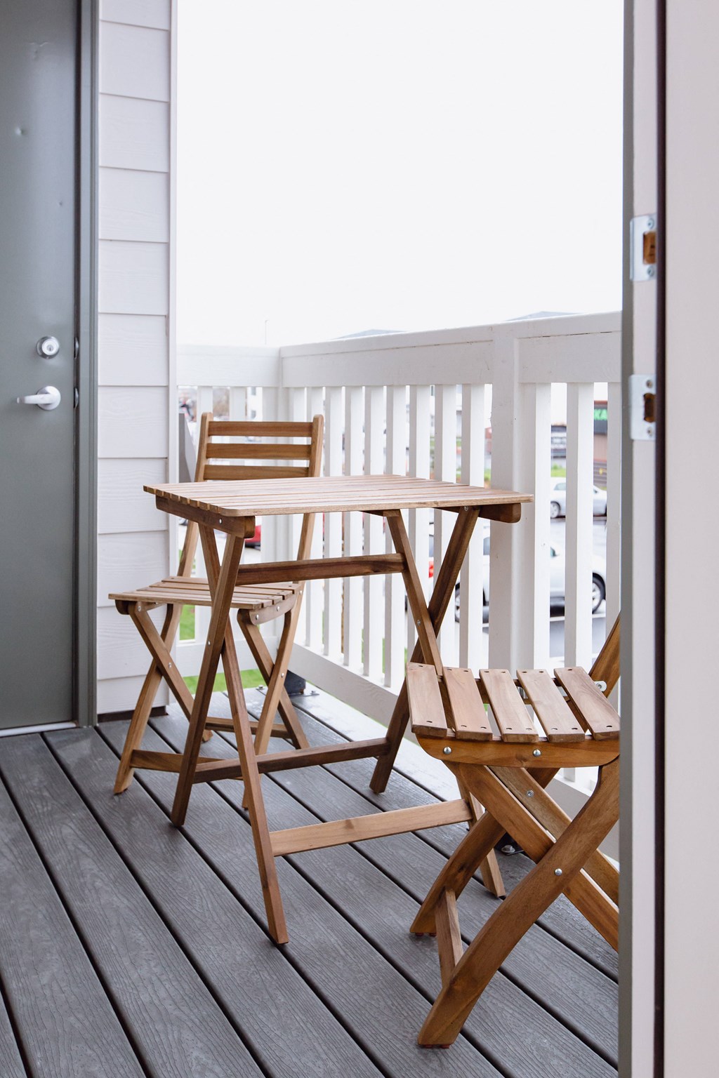 two wooden chairs and a table on a balcony