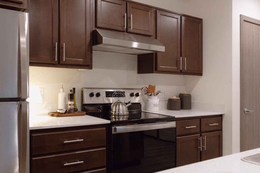 a kitchen with dark wood cabinets and a stainless steel stove