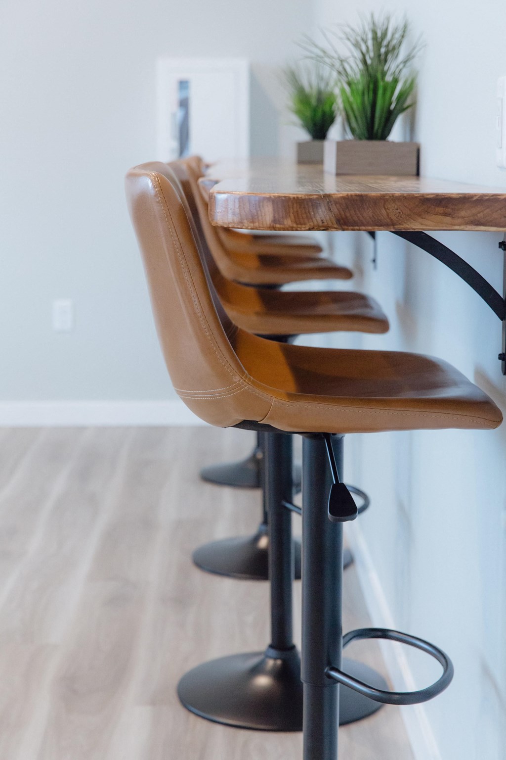 a row of bar stools in a kitchen with a wooden table and leather chairs