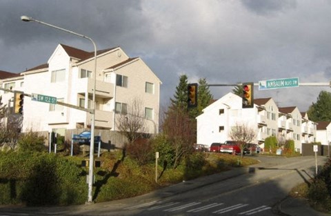 A street view of a residential area with houses and a street sign.