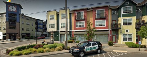A sheriff car is parked in front of a building with a clock tower.