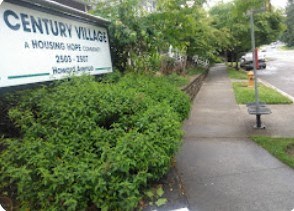 A sign for Century Village reads "A Housing Hope Community" and includes a phone number.