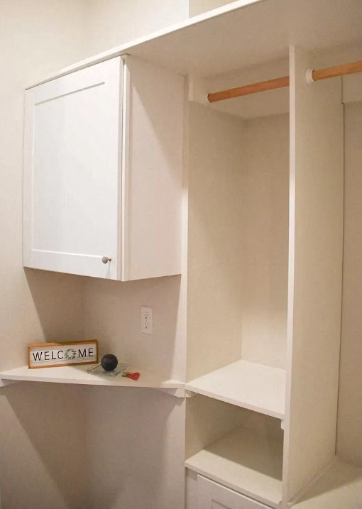 an empty bathroom with white cabinets and a white shelf