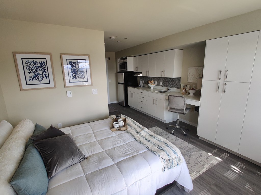 a bedroom with a bed and a kitchen