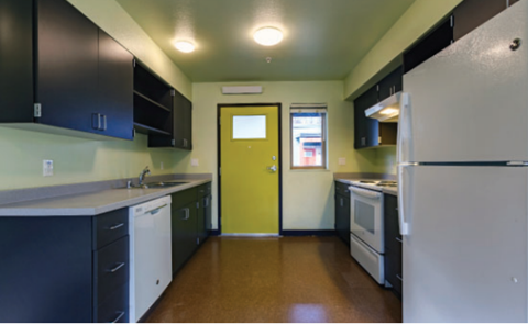 A kitchen with a yellow door and white appliances.