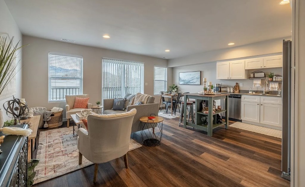 A well-lit living room with a kitchen area in the background.
