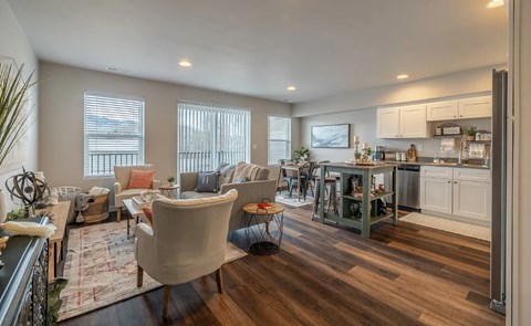 A well-lit living room with a kitchen area in the background.