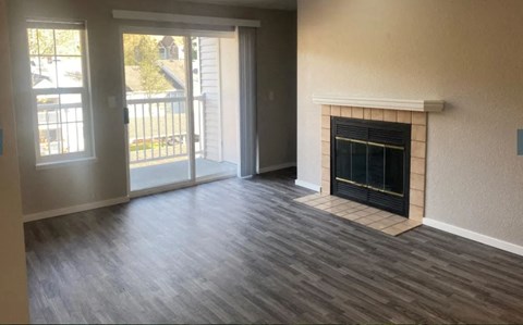 an empty living room with a fireplace and a sliding glass door