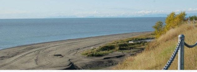 a dirt road next to the ocean and a fence
