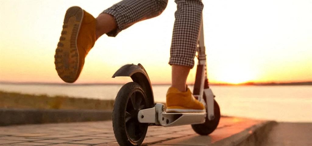 a person riding a segway scooter on a sidewalk at sunset