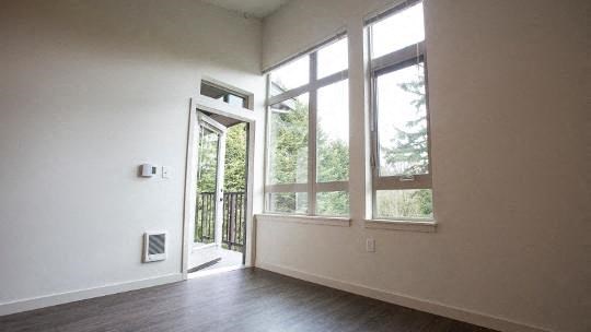 an empty living room with large windows and a door