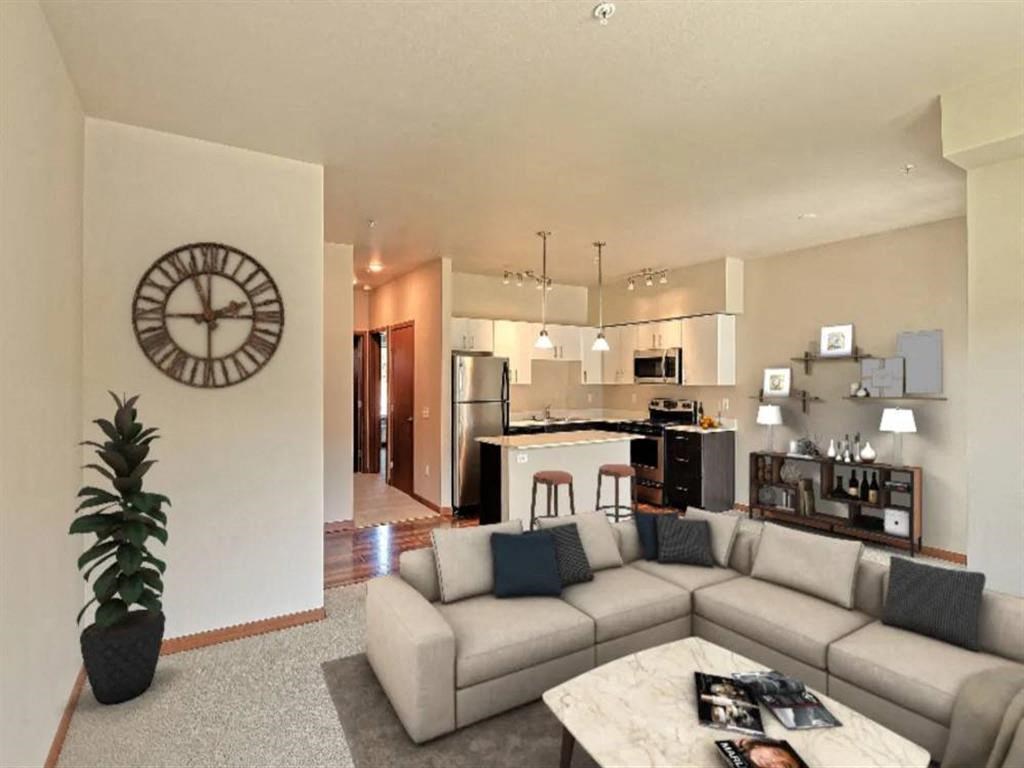 a living room and kitchen with a couch and a clock on the wall