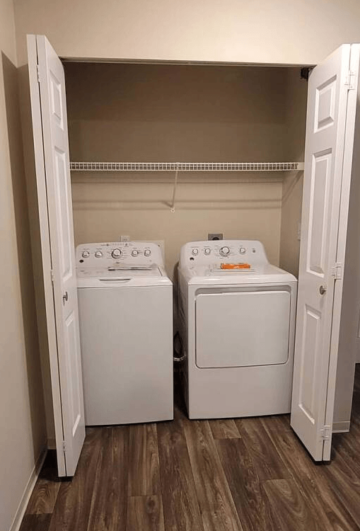 two washers and dryers in a room with a closet