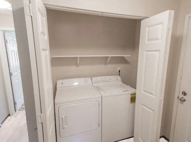 A white washing machine sits in a small, white-walled laundry room.