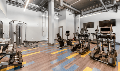 a gym with cardio machines and weights on a wooden floor