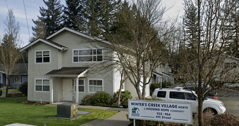 A sign for Winter's Creek Village North is in front of a house.